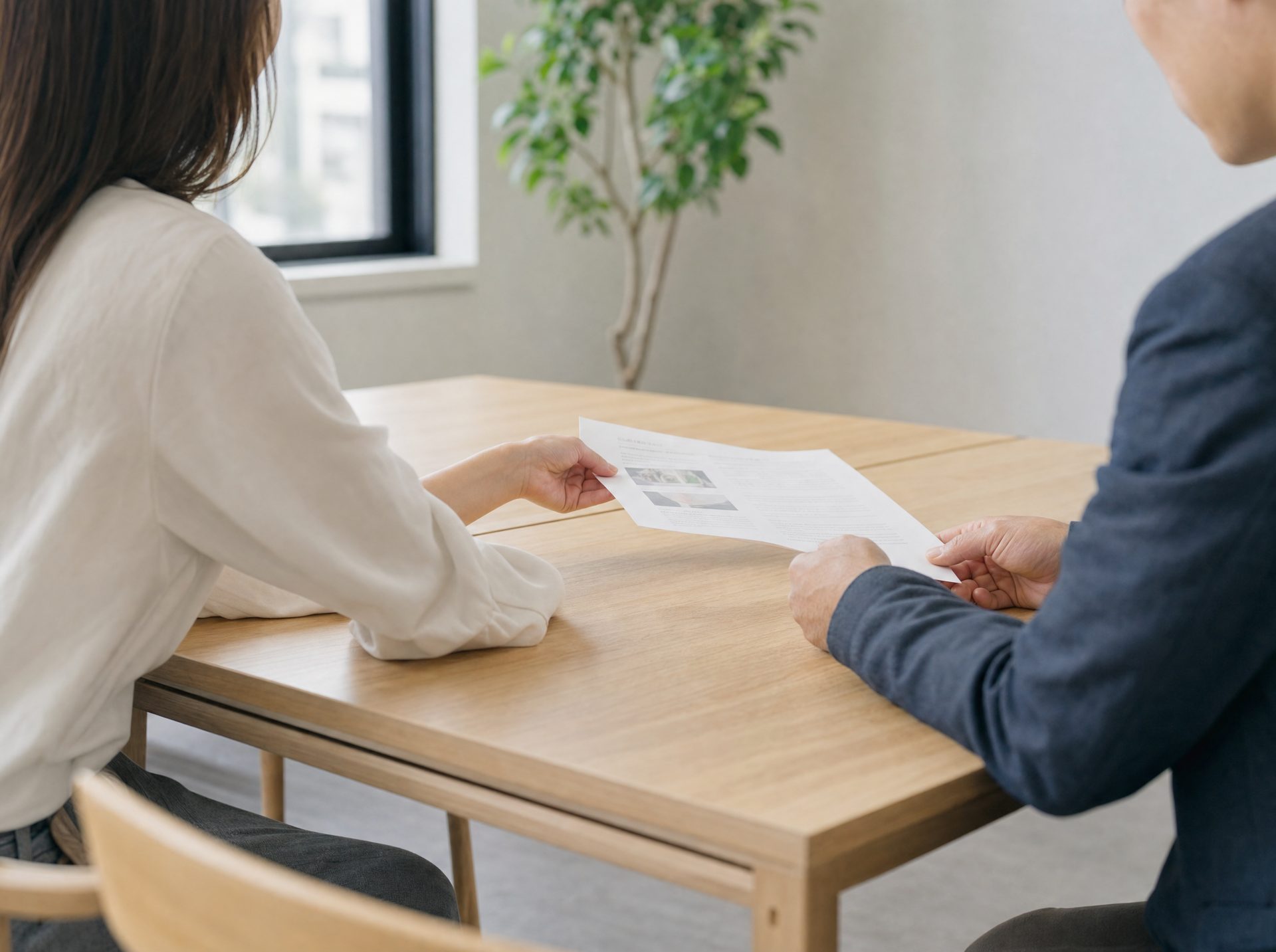 Deux personnes à une table, un document glissé de l’une à l’autre