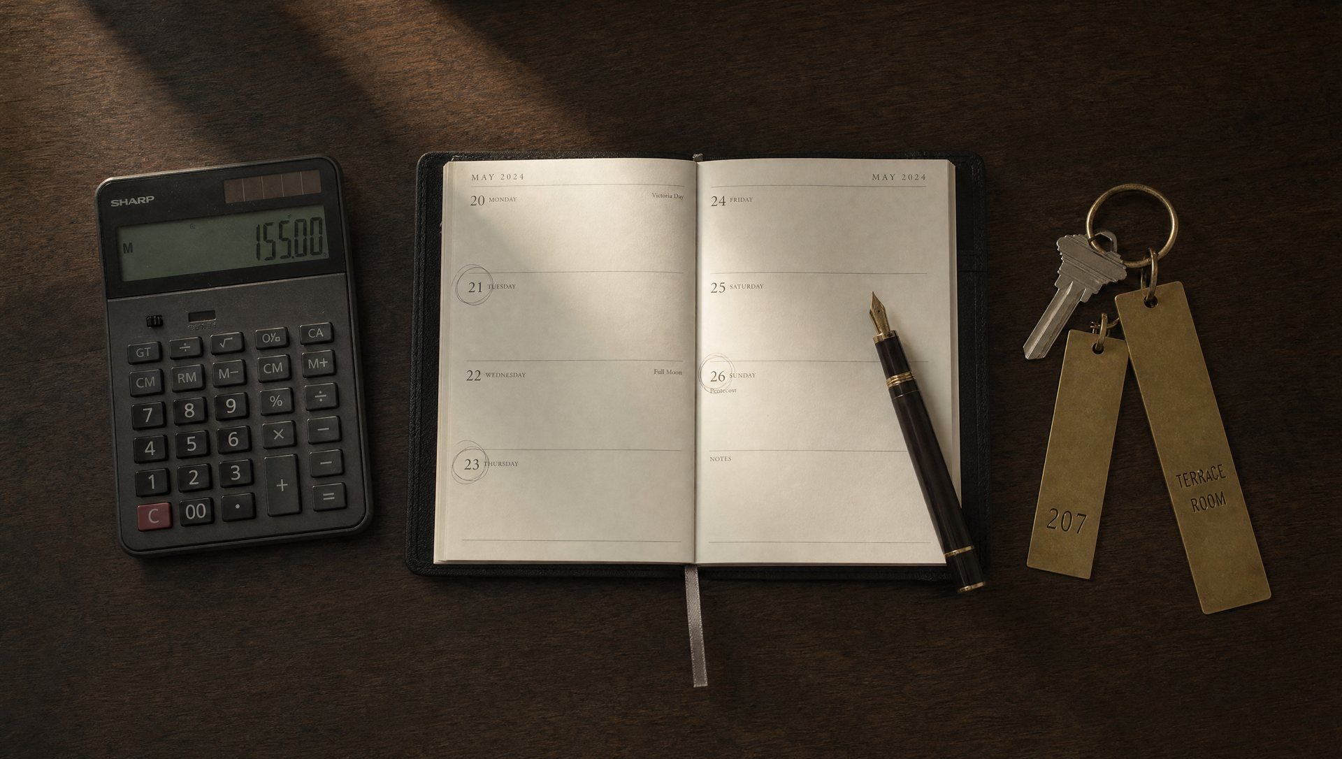 Sur un bureau, une calculatrice, un agenda annoté, un stylo et les clés des salles